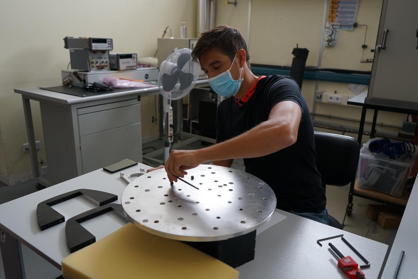 Imagen de Pablo de Chaves, ingeniero de IACTEC, ensamblando el útil de test para los ensayos de vibración del instrumento DRAGO en las instalaciones del Área de Ensayos del INTA (Instituto Nacional de Técnica Aeroespacial). Crédito: Alba Peláez (IAC).
