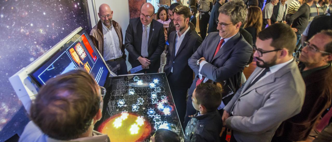 The Director of the IAC, Rafael Rebolo, the President of the Cabildo of Tenerife, Carlos Alonso, the director of the ACIISI, Juan Ruiz Alzola, and the Director General of Culture of the Canarian Government, Xerach Gutiérrez Ortega, with the Curators of the "Lights of the Universe" Exhibition, together with members of the public in the module "Scientific Highlights of the IAC". Credits; Daniel López /IAC 