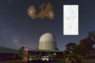 Las Nubes de Magallanes sobre el Telescopio Anglo-Australiano (AAT, Observatorio de Siding Spring, Australia). Superpuesto en falso color se muestra la distribución de gas atómico en ambas galaxias enanas y el Puente de Magallanes conectando las dos. El r