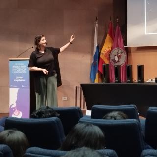 La divulgadora señala al público un área del cielo que aparece en la pantalla